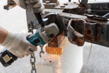 Bir metal parçasını kesmek için metal öğütücü kullanan bir işçi.