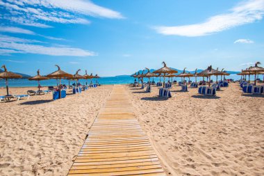 Kumlu sahilde şemsiyeleri ve sandalyeleri olan güzel bir sahil.