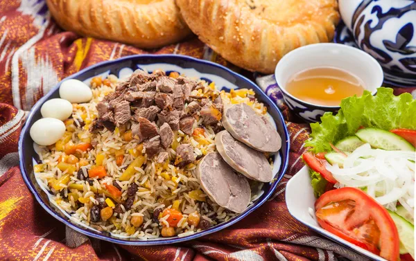 Comida nacional uzbeka en adras de tela tradicional — Foto de Stock