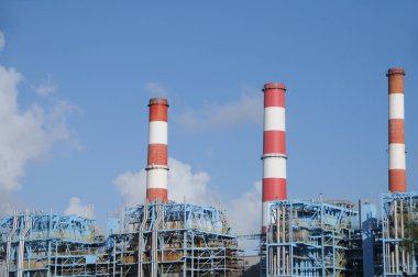 Industrial refinery facility with red and white smoke stacks