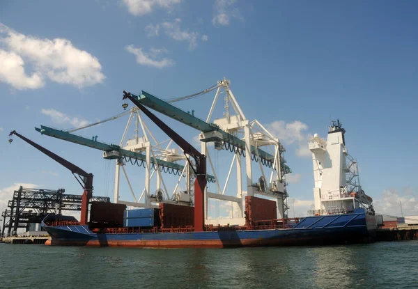 Cargo ship is being loaded in a large industrial port US East Coast