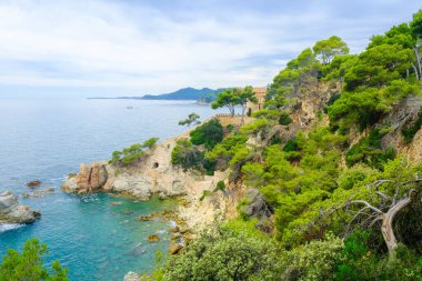 İspanya, Lloret de Mar 'da Akdeniz' in kayalıkları bulutlu havada.