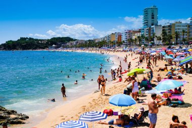 LLORET DE MAR, SPAIN - 29 Temmuz 2019: güneşli bir günde şehir plajı, bir sürü güneş sandalyesi ve şemsiyeyle. Costa Brava. Plaj istirahatı kavramı. Yaz seyahati.