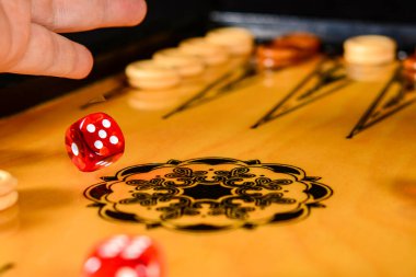 Tavla oyunu. Oyuncu zarları tahtaya fırlattı ve bir tane de havada..