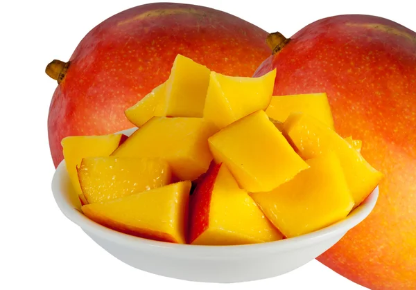 Dos mango entero y mango en cubos en un plato con fondo blanco — Foto de Stock