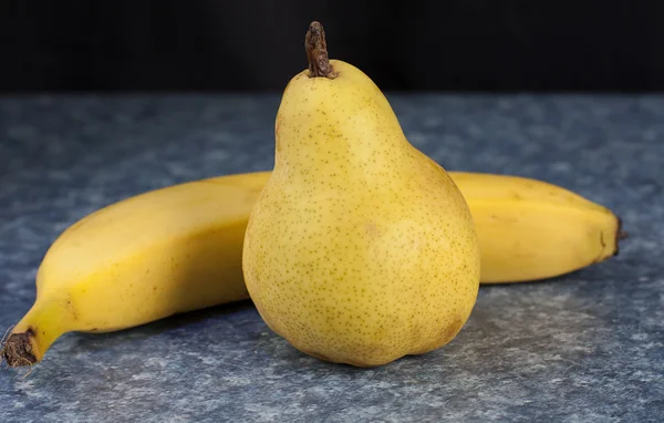 Peer en banaan op tafelblad — Stockfoto