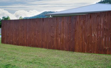 Güvenlik ve mahremiyet için evin etrafındaki koyu ahşap çitler.