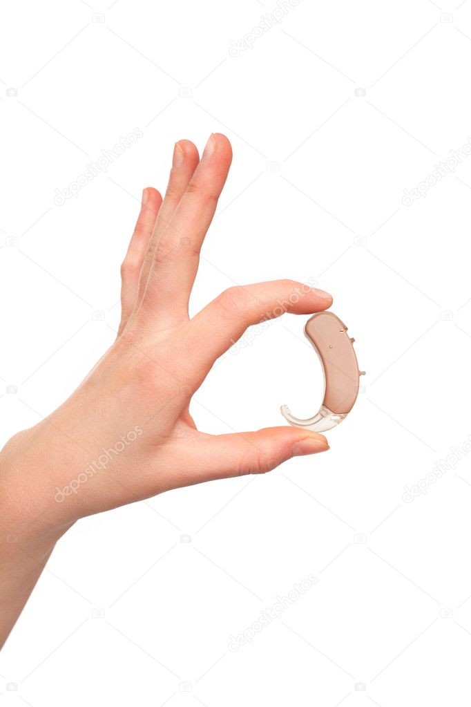 Hearing aid without ear mould and tubint between young female hand's fingers.