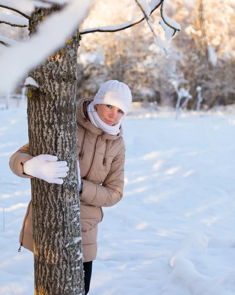 Девушка за деревом зимой — стоковое фото