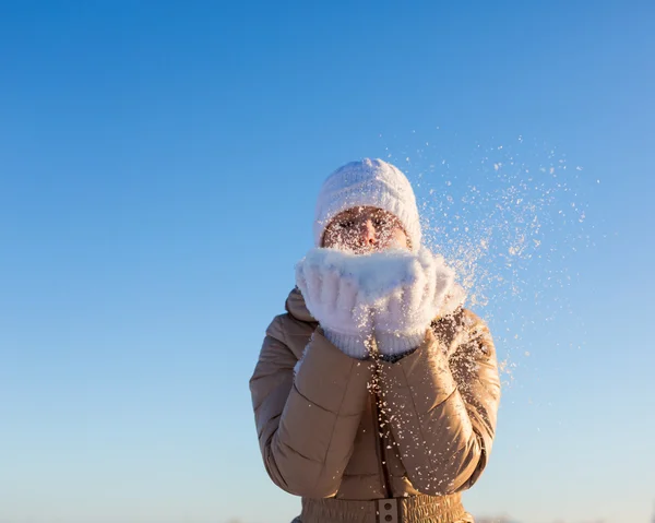 Young girl blows away snow off hands — Stock Photo, Image