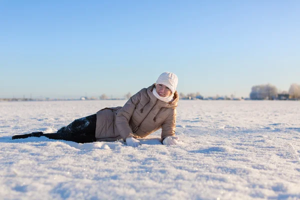 Ung flicka ligger på en snöig fältet — Stock fotografie