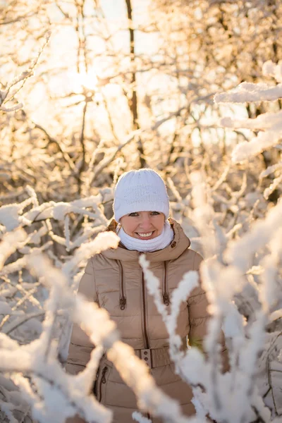 Ung flicka leende i den snöiga skogen — Stockfoto