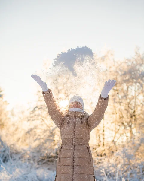 Молодая девушка бросает снег на солнечном фоне — стоковое фото