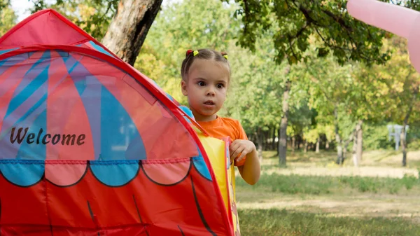 Маленькая девочка, заглядывающая в маленькую палатку — стоковое фото
