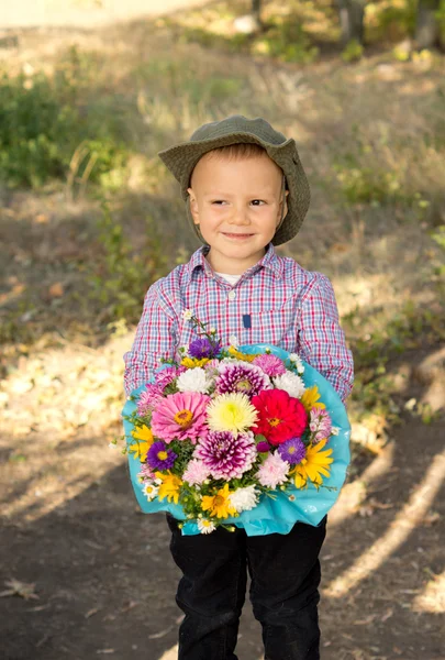 Usměvavý mladý chlapec s květy — Stock fotografie
