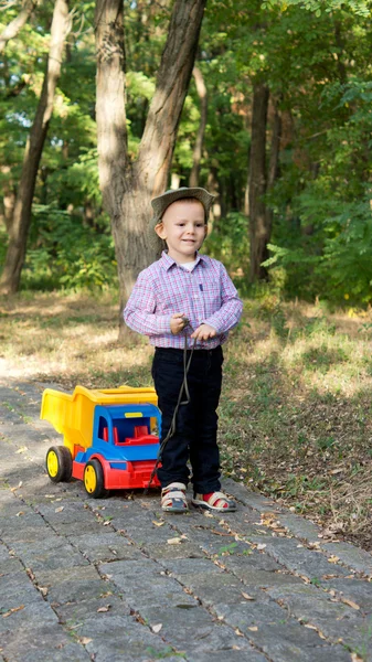 Boy pulling a toy truck on a paved lane — Stock Photo, Image