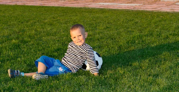 Liten pojke liggande på grönt gräs — Stockfoto