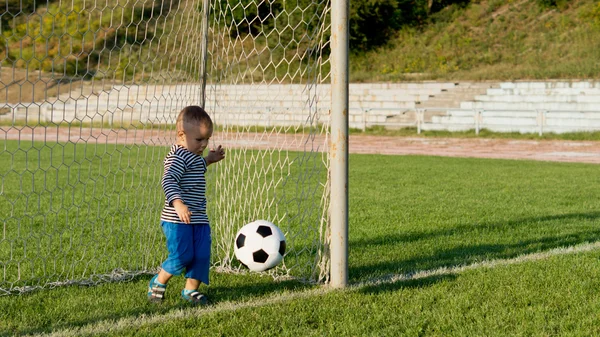 Liten pojke sparka en fotboll — Stockfoto