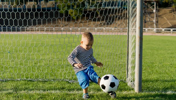 Petit garçon frappant un ballon de football — Photo