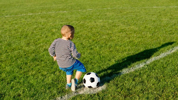 Liten pojke sparka en fotboll — Stockfoto