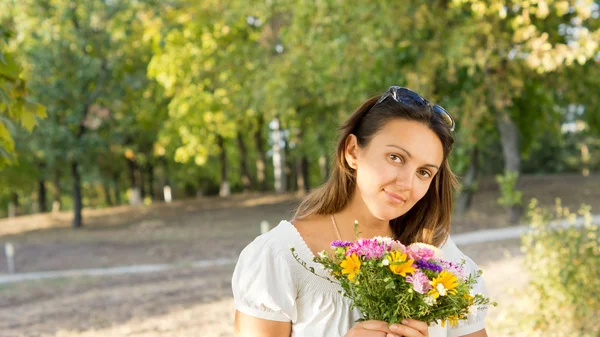 Mulher atraente segurando um monte de flores — Fotografia de Stock