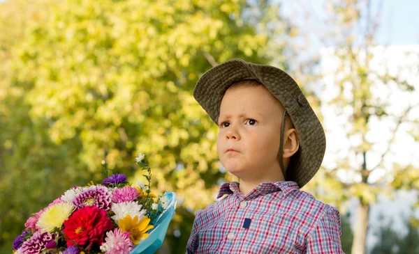 Обеспокоенный мальчик с цветами — стоковое фото