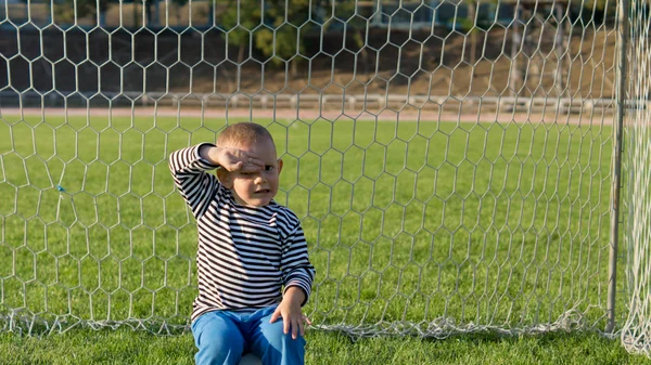 Liten pojke sitter i målstolparna — Stockfoto