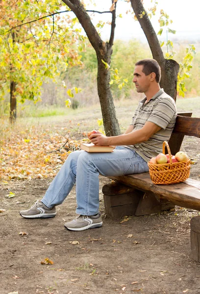 Mann sitzt und isst Äpfel — Stockfoto