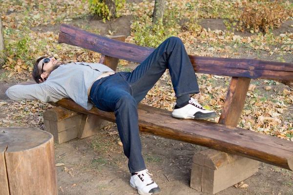 Mann schläft auf Holzbank — Stockfoto