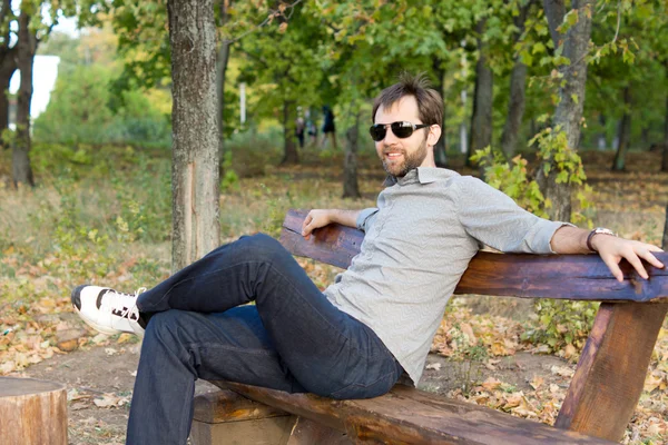 Uomo sorridente che si rilassa su una panchina del parco — Foto Stock