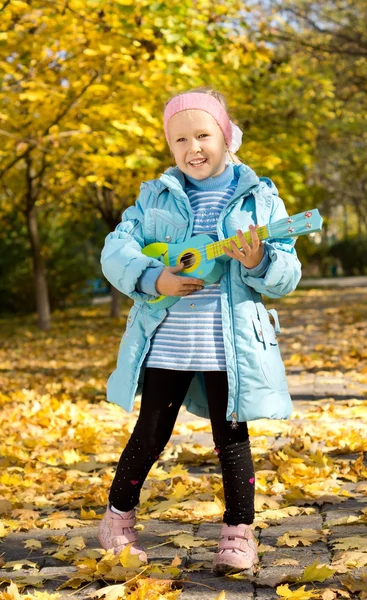 Schattig klein meisje een speelgoed gitaarspelen — Stockfoto