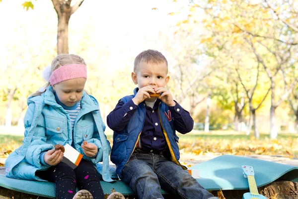 Lindos niños disfrutando de un aperitivo al aire libre — Foto de Stock