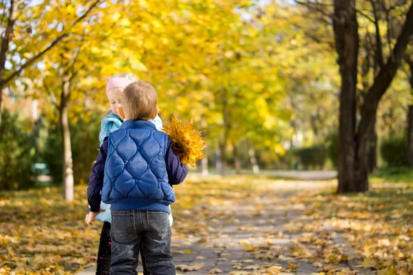 Jeune garçon et fille avec feuilles d'automne jaunes — Photo