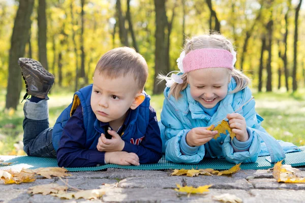 Μικρά παιδιά, χαλαρώνοντας σε ένα πάρκο φθινόπωρο — Φωτογραφία Αρχείου