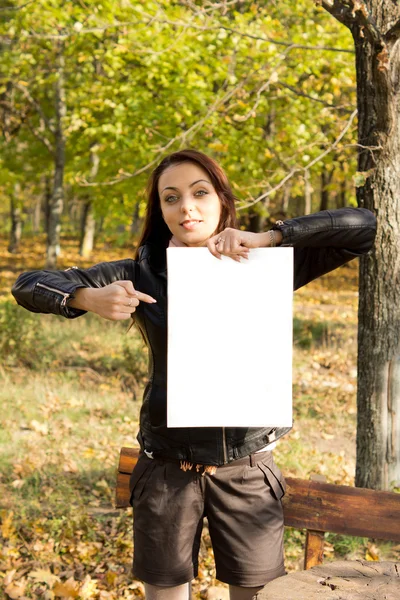 Mujer sosteniendo un cartel en blanco en el bosque — Foto de Stock