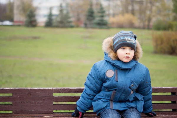 Kid sitting on a bench in the garden — Stok fotoğraf