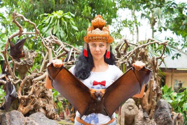 Woman in headdress holding a flying fox — Stock Photo, Image
