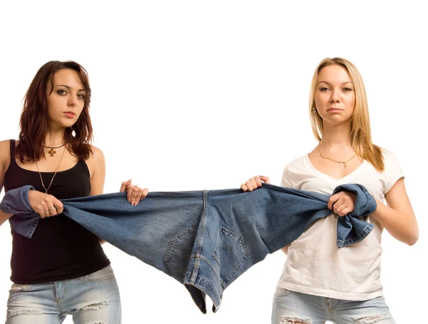 Duas meninas infelizes puxando um par de jeans — Fotografia de Stock