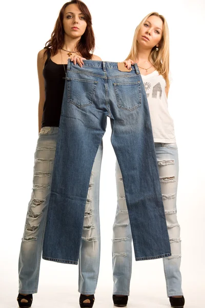 Two girls holding up a pair of jeans — Stock Photo, Image