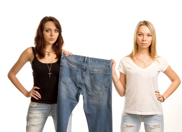 Two sexy friends posing with a pair of jeans — Stock Photo, Image