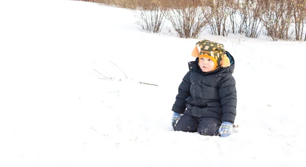 Cute little boy kneeling in winter snow — Stock Photo, Image