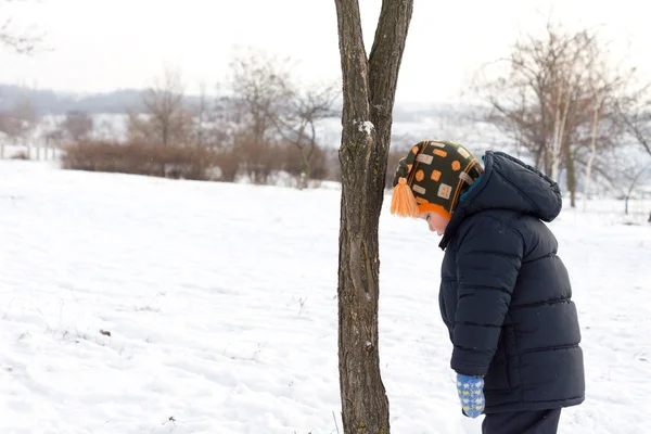 Small boy looking down at the winter snow — Stock Photo, Image