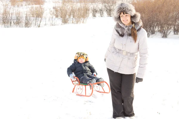Mor bogsering hennes son i snön — Stockfoto
