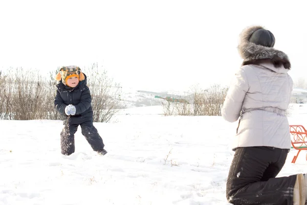 在他的母亲扔雪球的小男孩 — 图库照片