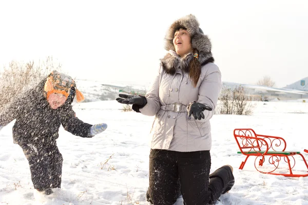 Pequeño niño jugando en la nieve con mamá — Foto de Stock