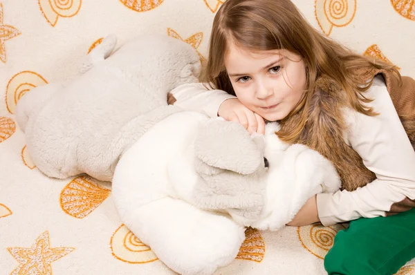 Милая маленькая девочка обнимает мягкую плюшевую игрушку — стоковое фото