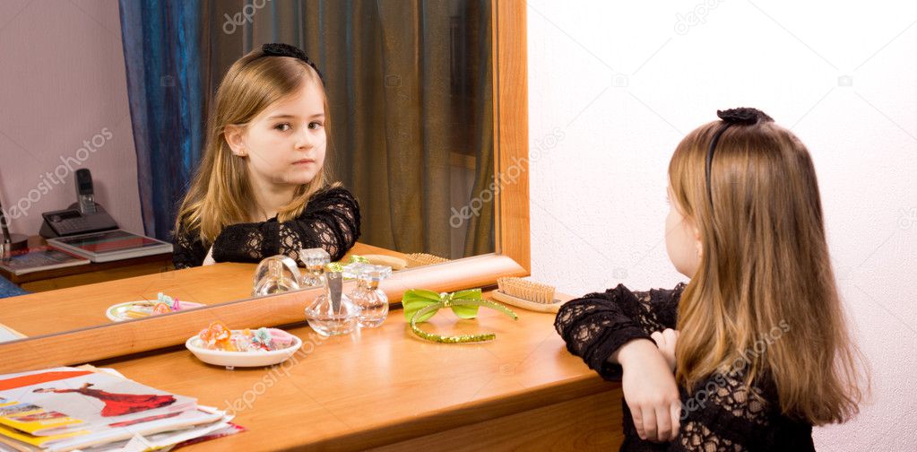 Little girl looking at herself in a mirror