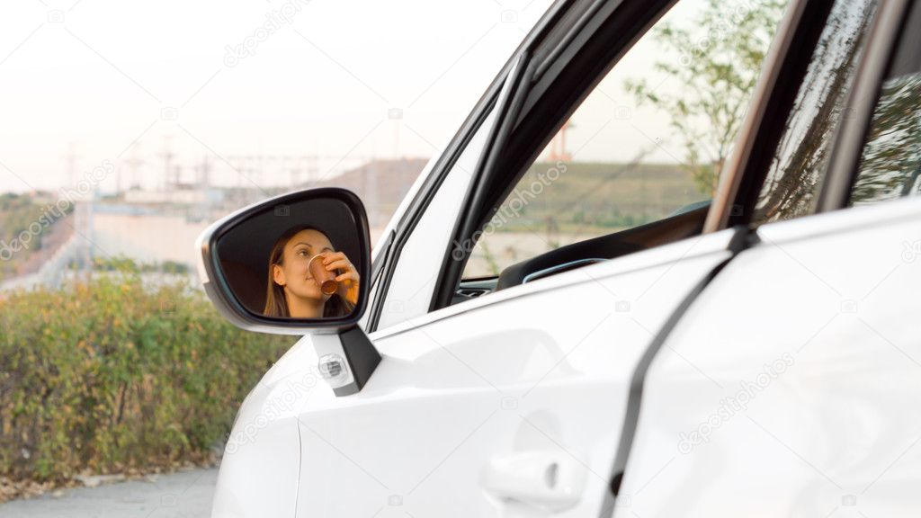 Woman drinking refreshment in her car