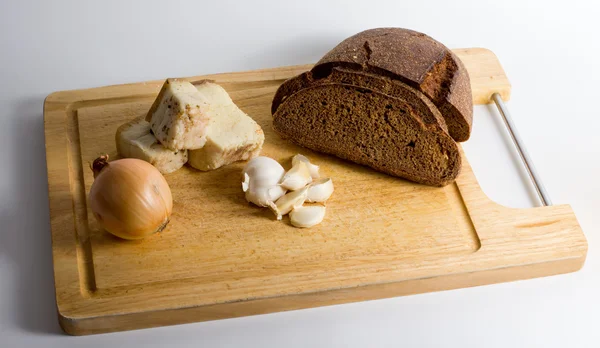 Tabla de madera con pan, manteca de cerdo, ajo y cebolla —  Fotos de Stock