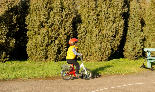 Aktiv liten pojke ridandes på sin cykel i parken — Stockfoto